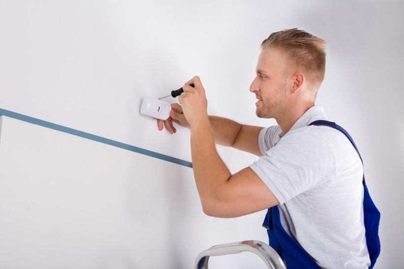 l'homme installe un détecteur de mouvement