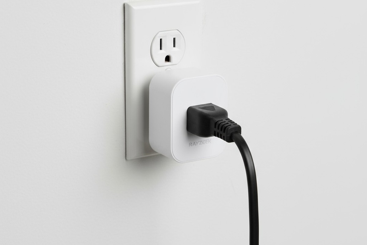 一個白色動作感應插頭的近距離圖像，插入一個壁式插座，一條黑色的暖氣便攜電源線插在它上面。