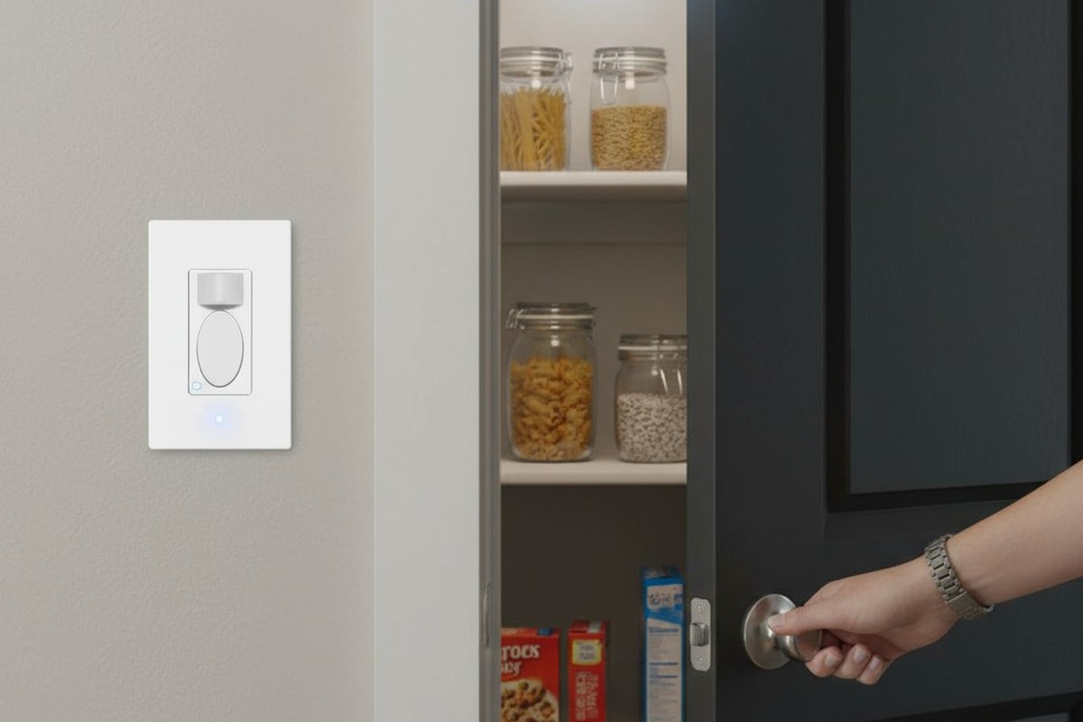 La mano de una persona alcanza un pomo de la despensa, y un interruptor de sensor de movimiento en la pared acaba de encender la luz brillante en el interior.