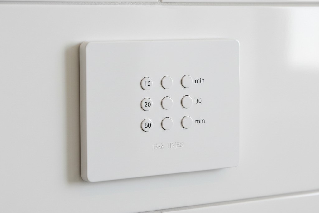 Countdown timer switch for exhaust fan A white wall-mounted switch with vertical buttons labeled with time increments like 10, 20, 30, and 60 minutes.